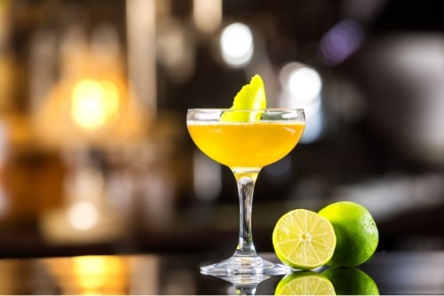 an orange cocktail in a glass next to lime slices