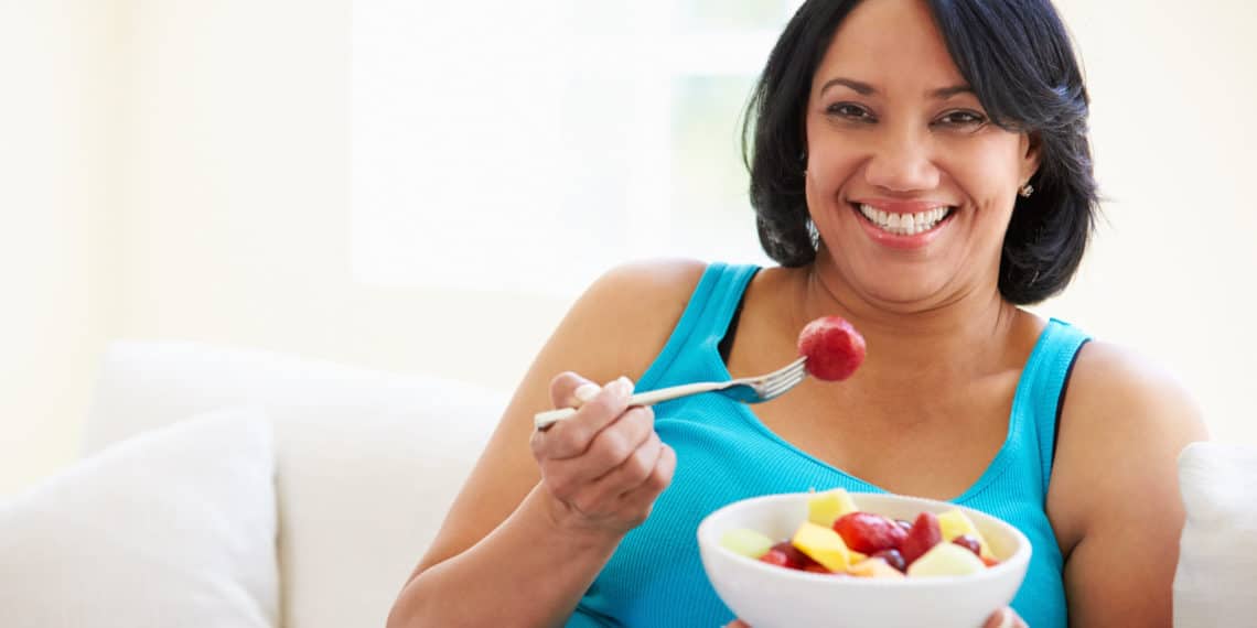 woman eating colorful fruit salad with strawberries