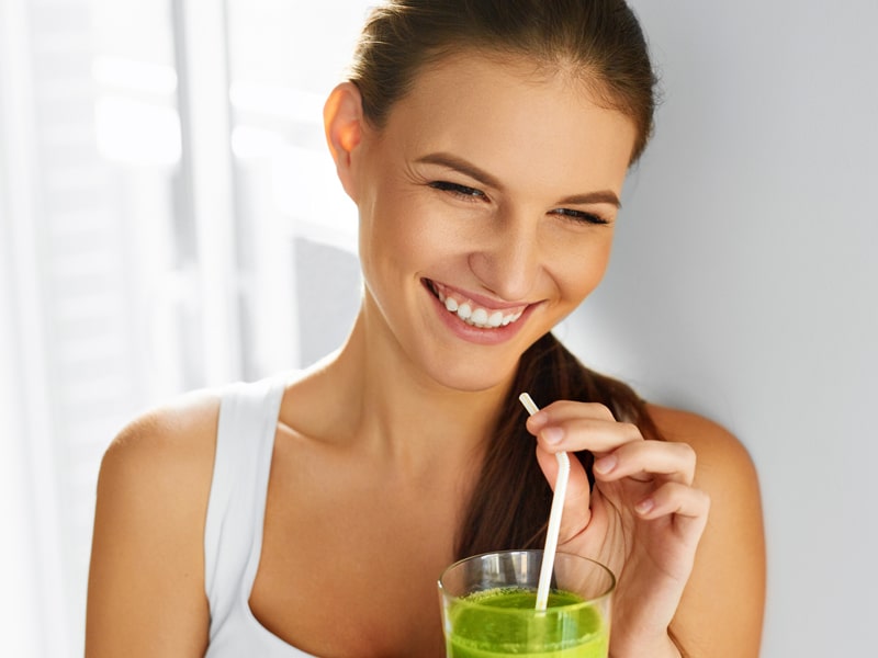 woman drinking a green smoothie