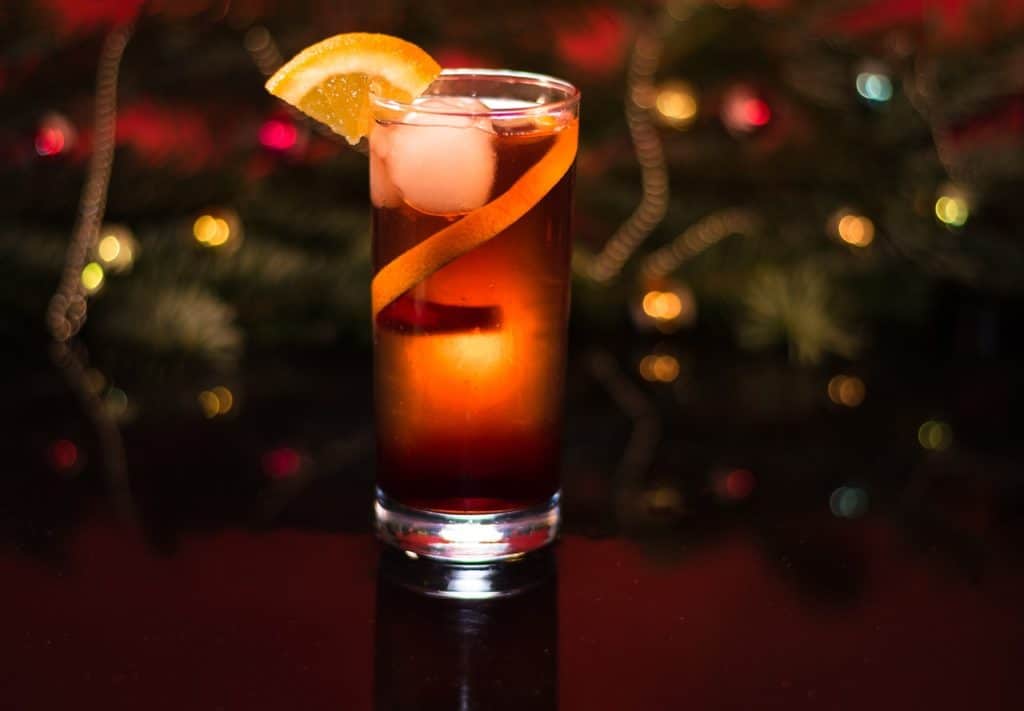 a festive cocktail in front of a Christmas tree with lights