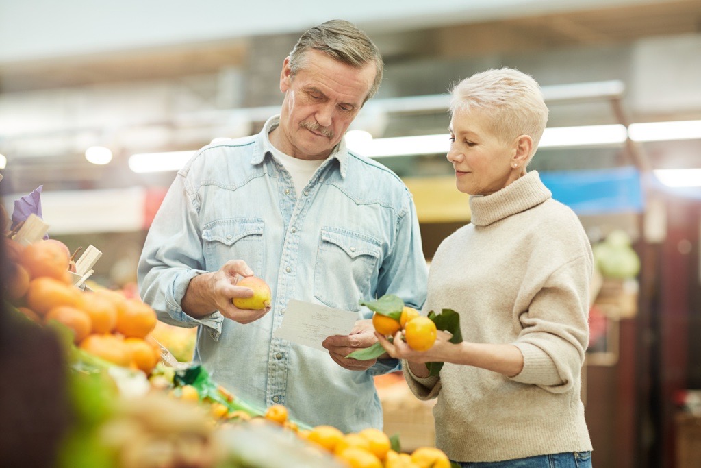 Two people looking at produce in a grocery store