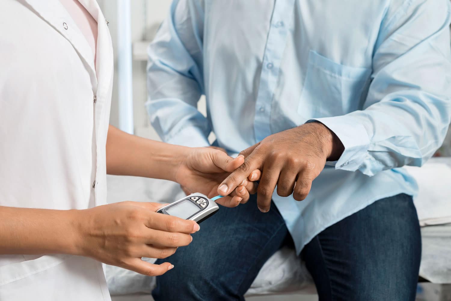 man being finger pricked in doctor&rsquo;s office