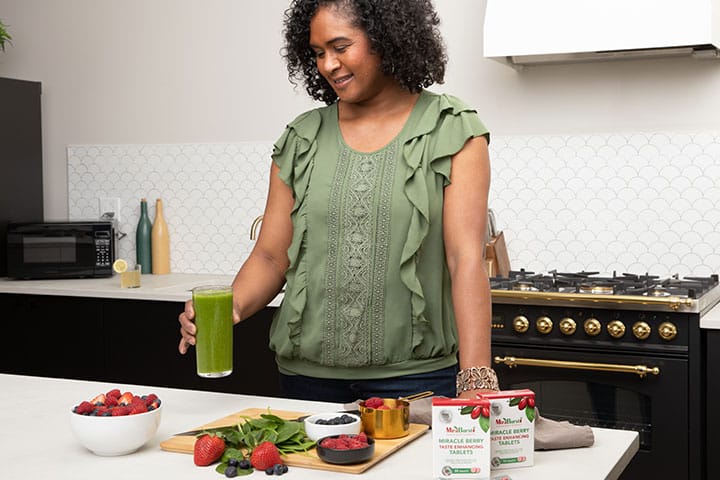 woman smiling while holding glass of juice